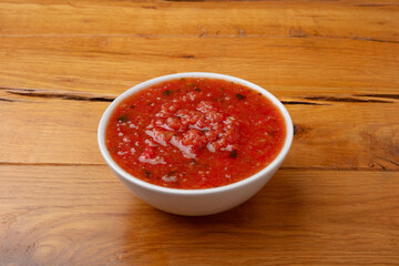 Red salsa in a white bowl on a wood table 