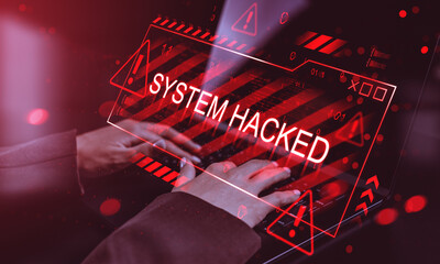 System hacked warning alert with red digital sign over keyboard and hands typing on laptop in dark environment showing online virus attack concept.
