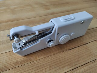 Portable sewing machine on the wooden background