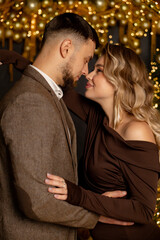 Fototapeta premium A guy with a girl is celebrating Christmas. A loving couple enjoys each other on New Year's Eve in a cozy home environment. New Year's love story 