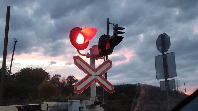 Working semaphore at a railway crossing, prohibiting entry, against the backdrop of the evening sky