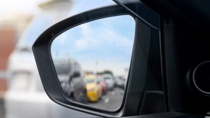 Mirror view from the side of the car. Heavy traffic during rush hour reflected in the car side mirror. Clear sky traffic conditions.