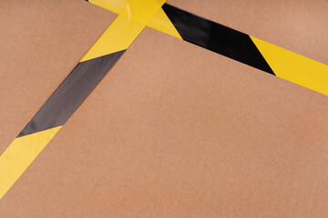 Black and yellow striped сaution tape on cardboard background. prohibitory warning tape packaging...