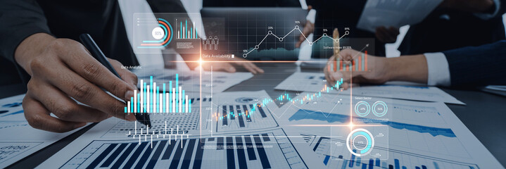 Business professionals engaged in data analysis with reports and digital tools, focusing on...