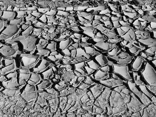 Dry cracked desert ground in Monument Valley under bright sunlight with iconic rock formations