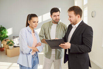 Realtor or real estate agent showing a couple a new house before purchase or rent. Presents the...