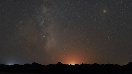 Fototapeta premium On Desert Silhouettes, A Nighttime Rhapsody of Galaxy and Earthly Glow