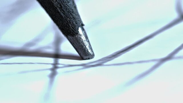 An extreme macro shot showing a pencil tip in motion, emphasizing the texture of the graphite and paper, suggesting intense focus and the start of a creative process
