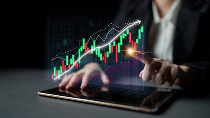 A business professional interacts with a tablet displaying stock market trends through digital graphs, emphasizing analytics in a dark setting for impactful financial insights. Impute