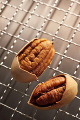 Close-up of opened pecan nuts with kernels on a metal grill mesh, natural texture and lighting, food photography