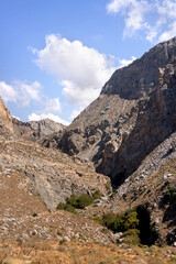 collection of photographs showcasing the dramatic natural beauty of the Kourtaliotiko Gorge in Crete. The images highlight steep rocky cliffs, winding river streams, lush vegetation