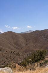 calm, dry and sun-baked mountains of Crete open up under wide blue sky. Natural, authentic Mediterranean nature with gentle hill lines, rocky slopes and subtle summer light. Suitable for illustration