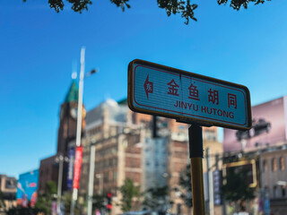 Obraz premium Street sign of Beijing’s Jinyu Hutong, one of the city’s busiest shopping and pedestrian streets on a sunny day.
