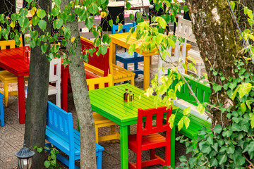 Vibrant wooden tables and chairs in an outdoor countryside café create a lively, inviting, and charming rustic atmosphere