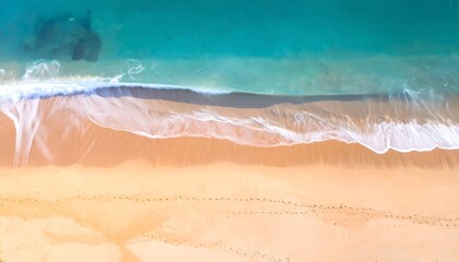 Aerial view of ocean waves meeting golden sandy beach, showing footprints near the shoreline