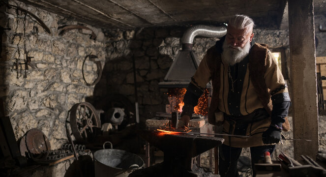 A Viking blacksmith with a white beard and braided hair works intently at a forge, hammering glowing metal on an anvil, with flames flickering in the background of a stone workshop.