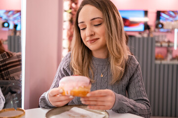 Delighting in a pink frosted donut during a casual cafe visit with friends