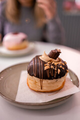 Delicious donut topped with chocolate and nuts on a plate in a cozy cafe setting