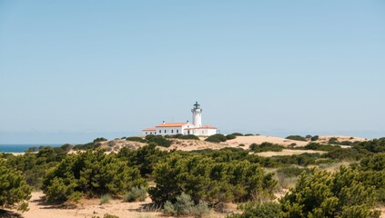 Peaceful lighthouse standing tall on a dune against a clear blue sky in tarifa, spain, europe