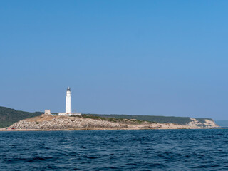 Wide view of the lighthouse and coastline seen from the ocean.