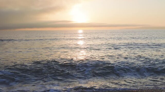 Black Sea and beach nearby against a sky with clouds and a dawn sun