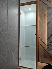 Clear glass cabinet with light wood material and some white lights make it look luxurious