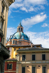 Santa Maria Della Vita Catholic Church stands prominently in Bologna, Italy, showcasing its captivating dome against a bright blue sky. Nearby buildings add to the charm of the scene.