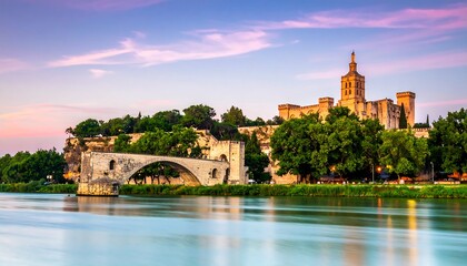 Fototapeta premium Ancient structure on a river bank with arch bridge under pink sunset sky with trees