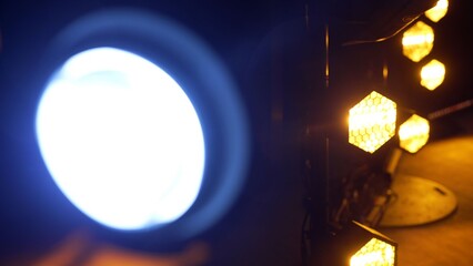 Stage lights illuminating a dark concert venue, creating a dynamic background with blurred bright bokeh and glowing patterns