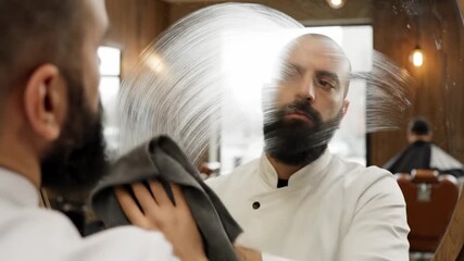 POV cinematic video footage of a barber wiping a client's face while standing in front of a mirror, emphasizing grooming care and barbershop atmosphere.
