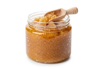 Glass jar filled with granulated brown sugar scrub rests beside a small wooden scoop on a white background.