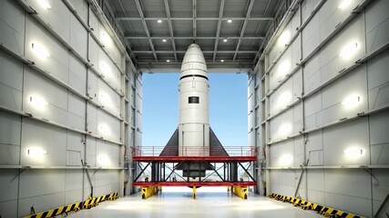 Large white rocket standing on a bright red and black mobile launch platform inside a well-lit, massive industrial hangar