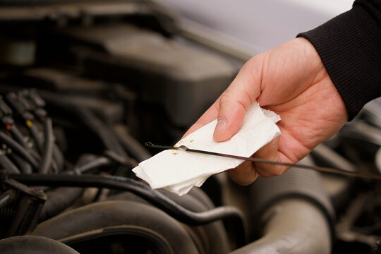 A man checking the engine oil level in a car using a dipstick