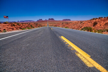 Desert road leading through Monument Valley with dramatic sandstone mesas and open scenery