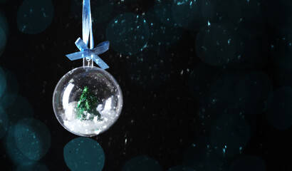Christmas ball with snow and fir tree inside against dark background. Banner design
