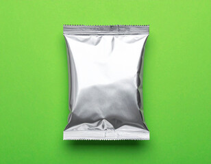 Minimalist Blank Silver Foil Snack Package Isolated on Bright Green Background for Branding, Product Mockup, and Packaging Design Presentation