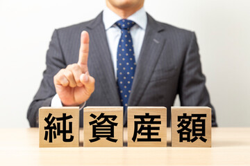 「純資産額」と書かれたブロックとビジネスマン