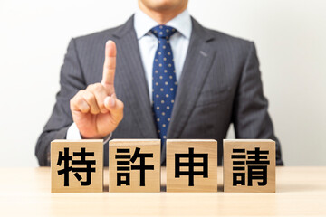 「特許申請」と書かれたブロックとビジネスマン