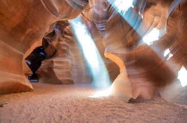 Sunlight creating dramatic patterns on sand and rock formations inside Antelope Canyon