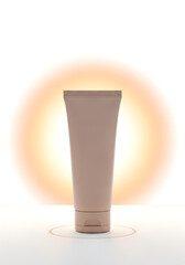 Minimalist studio shot of a light brown cosmetic tube with a warm glowing halo.