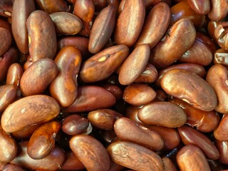 A full-frame, close-up background of plump, wet, cooked red kidney beans or similar legumes.