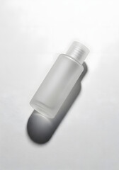 A small, frosted glass bottle with a white cap, casting a shadow on a white surface.