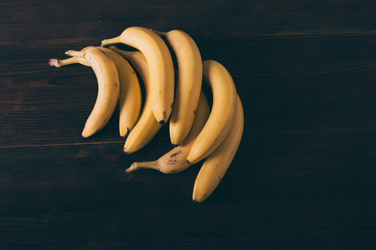 Bunch of bananas are sitting on a wooden table