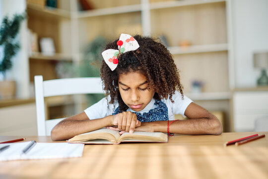 Portrait of a teenage girl having fun writing, reading a book  and doing homework at home - Powered by Adobe