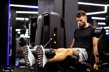 Naklejka premium Leg extension workout at gym during evening session for muscle growth and strength
