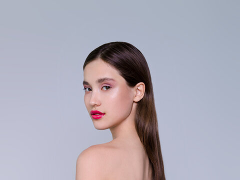 Beautiful brunette young woman with glowing make-up on blue background Fashion model close-up beauty shot stock photo