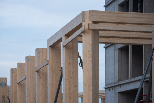 Close-up view of a timber construction site showing vertical glulam columns and wooden beams 