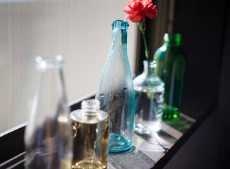 光を浴びる色付きガラスボトルと花