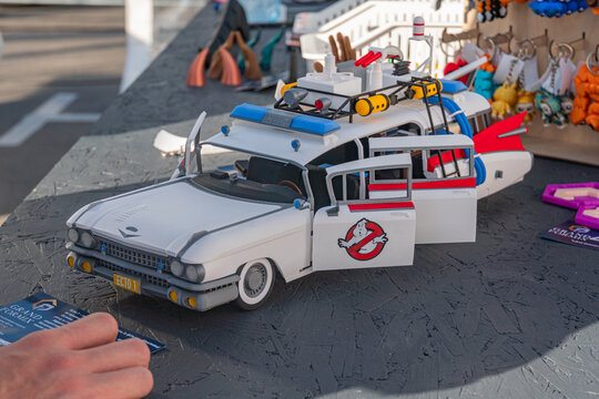 White Volkswagen VW bus with Ghostbusters design on a gray tarp surface, urban background, human hand holding blue card with text - Kyiv, Ukraine - September 21, 2025