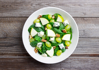 Salad with spinach, blue cheese, pear, grapes, and nuts. Healthy eating. Vegetarian.